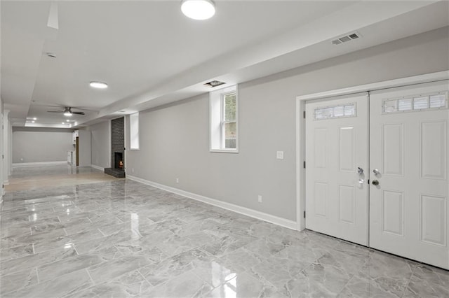 entryway with ceiling fan and a fireplace