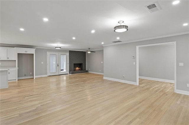 unfurnished living room with light hardwood / wood-style floors, a brick fireplace, ceiling fan, and crown molding