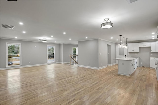 kitchen featuring light hardwood / wood-style flooring, white cabinetry, a kitchen island with sink, and ornamental molding