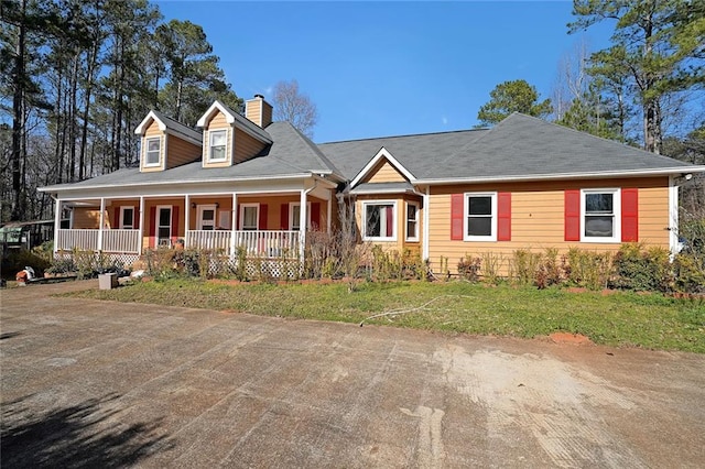 view of front of house with a porch, a chimney, and a front lawn