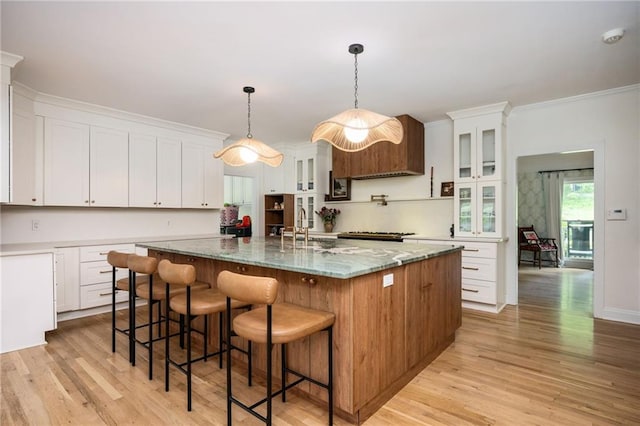 5102 Chastleton Dr, Stone Mountain, GA 30087 - kitchen with light wood finished floors, white cabinetry, a large island, glass insert cabinets, and light stone counters