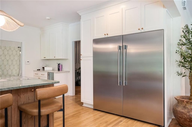 5102 Chastleton Dr, Stone Mountain, GA 30087 - kitchen featuring built in fridge, white cabinets, light wood finished floors, a kitchen bar, and light stone countertops