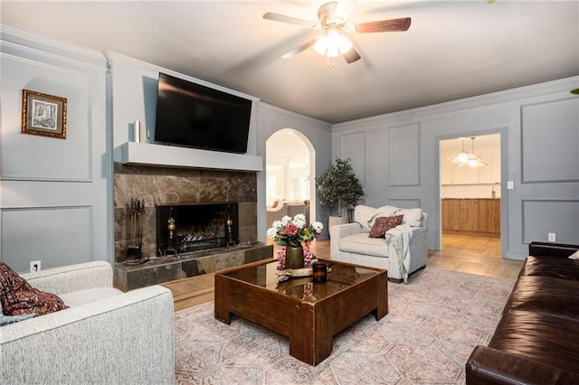 5102 Chastleton Dr, Stone Mountain, GA 30087 - living room with arched walkways, crown molding, ceiling fan, a tile fireplace, and a decorative wall