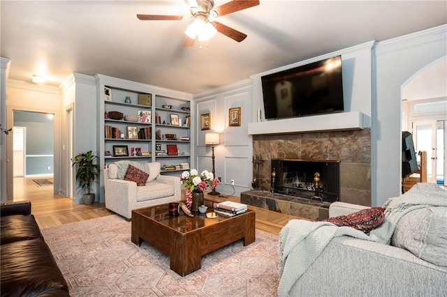 5102 Chastleton Dr, Stone Mountain, GA 30087 - living room featuring a ceiling fan, a tile fireplace, arched walkways, light wood-style flooring, and crown molding