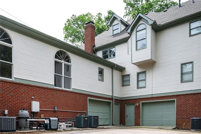 5102 Chastleton Dr, Stone Mountain, GA 30087 - rear view of house with brick siding, an attached garage, a chimney, and central air condition unit