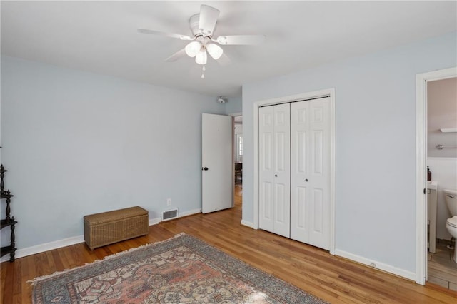 bedroom with ceiling fan, connected bathroom, a closet, and hardwood / wood-style flooring