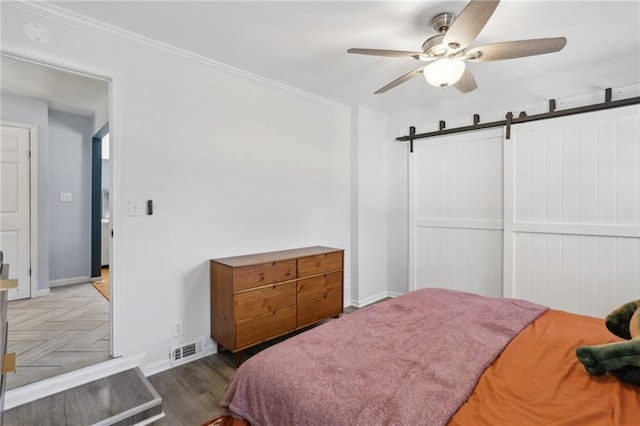 bedroom with ornamental molding, dark parquet flooring, ceiling fan, and a barn door