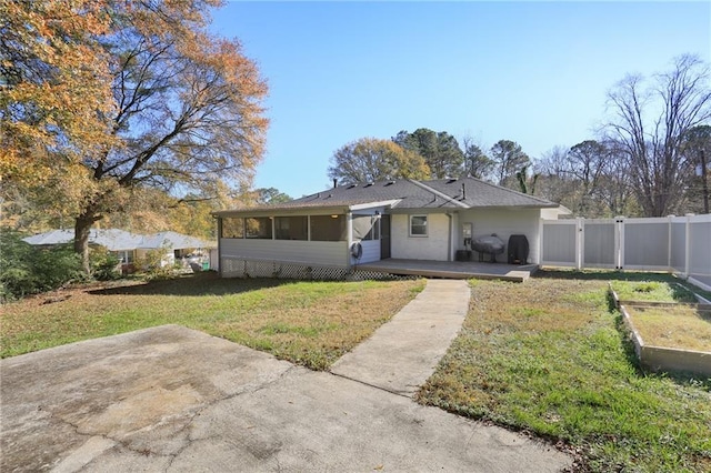 view of front facade featuring a sunroom, a patio area, and a front yard