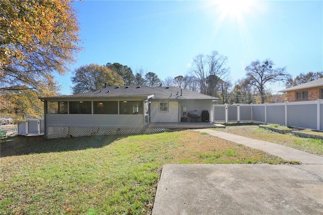 rear view of house featuring a patio area, a lawn, and a sunroom