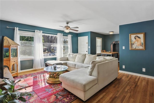 living room with a healthy amount of sunlight, dark wood-type flooring, and ceiling fan