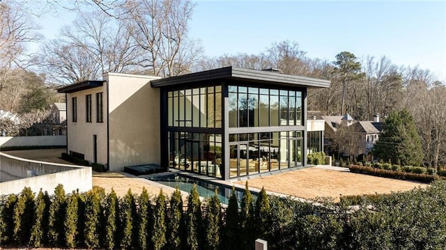 back of property featuring stucco siding, a swimming pool, and a sunroom