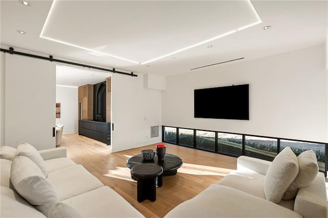 living area with recessed lighting, a barn door, light wood-style floors, and visible vents