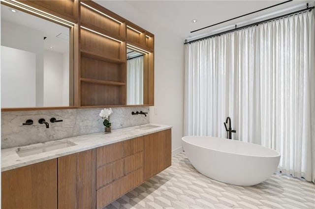 full bathroom featuring a freestanding bath, double vanity, backsplash, and a sink