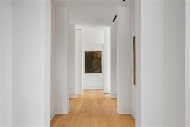 corridor featuring light wood-style flooring and baseboards