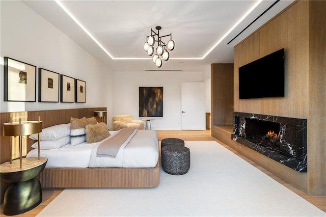 bedroom featuring a tray ceiling, wood finished floors, and a premium fireplace