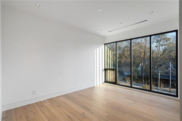 empty room with hardwood / wood-style floors, recessed lighting, and baseboards