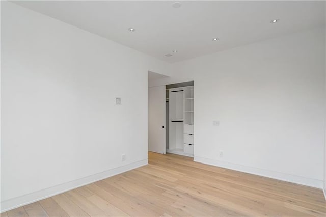 empty room featuring recessed lighting, light wood-type flooring, and baseboards