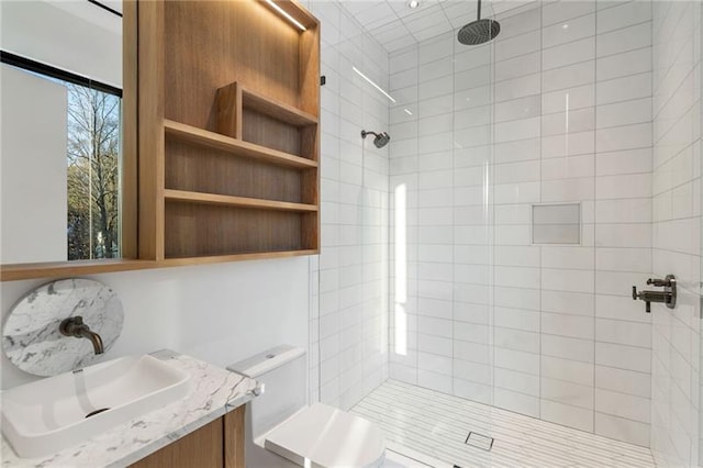 bathroom featuring tiled shower, toilet, and vanity