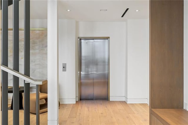 hallway featuring elevator, recessed lighting, and light wood-style floors