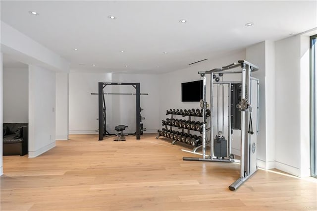 exercise room featuring recessed lighting, light wood-style floors, and baseboards