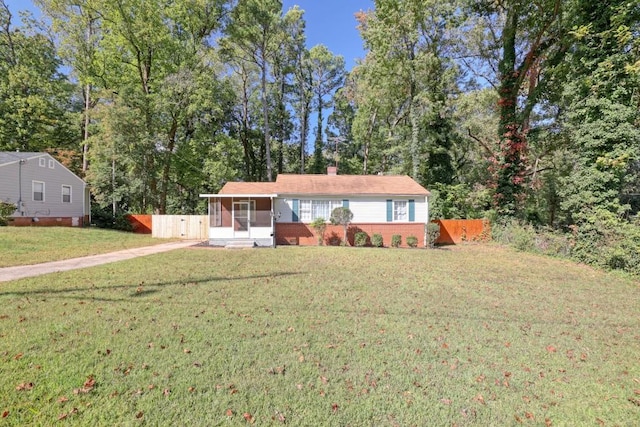 single story home with a sunroom, a chimney, fence, a front lawn, and brick siding