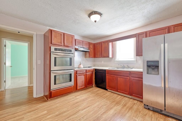 kitchen featuring black appliances, light hardwood / wood-style floors, a textured ceiling, and sink