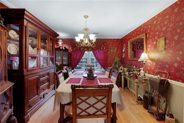 dining area featuring light wood-type flooring, crown molding, and a chandelier