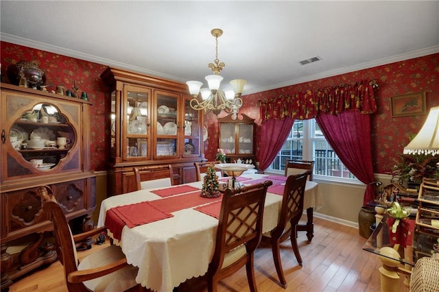 dining space with a chandelier, light hardwood / wood-style flooring, and ornamental molding