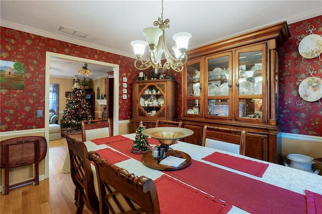 dining room with ornamental molding, light hardwood / wood-style flooring, and a chandelier