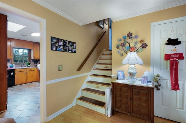 stairway with hardwood / wood-style flooring, crown molding, a skylight, and sink