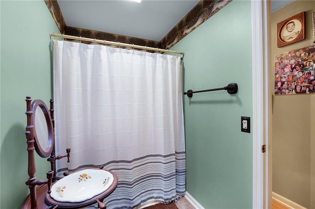 bathroom with beamed ceiling and a shower with shower curtain