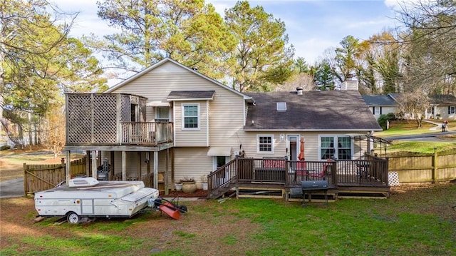 rear view of house featuring a wooden deck and a lawn