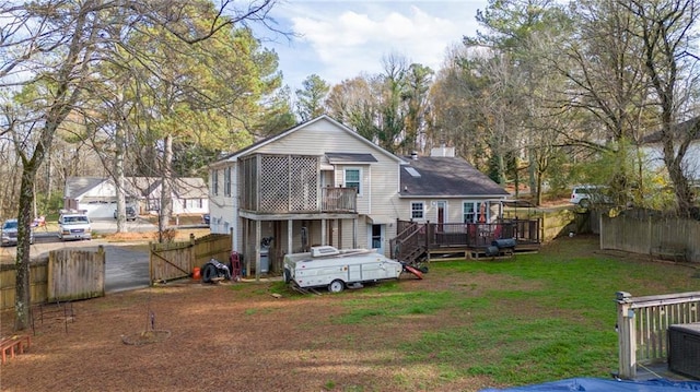 rear view of house featuring a lawn and a wooden deck