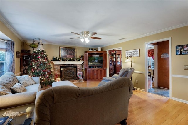 living room featuring a fireplace, ceiling fan, light hardwood / wood-style floors, and crown molding