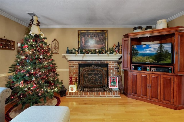 living room with light hardwood / wood-style floors, crown molding, and a fireplace