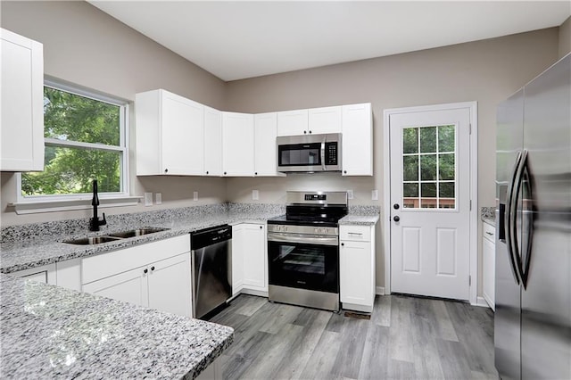 381 New Jersey Ave NW, Atlanta, GA 30314 - kitchen with appliances with stainless steel finishes, light stone counters, light wood-style floors, and white cabinets