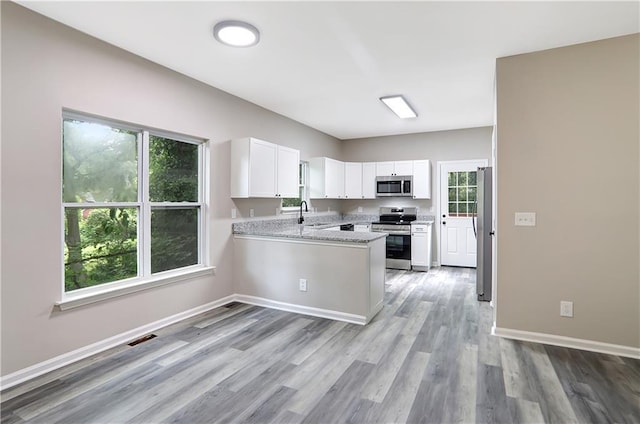 381 New Jersey Ave NW, Atlanta, GA 30314 - kitchen with appliances with stainless steel finishes, a peninsula, white cabinetry, and light wood-style flooring