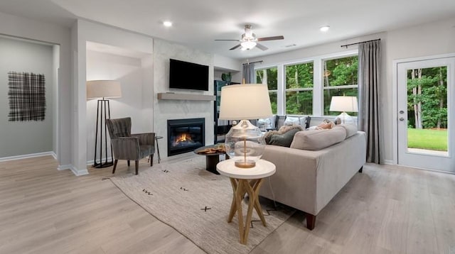 living room featuring light hardwood / wood-style floors, ceiling fan, and a fireplace