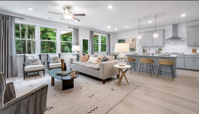 living room with ceiling fan and light hardwood / wood-style flooring