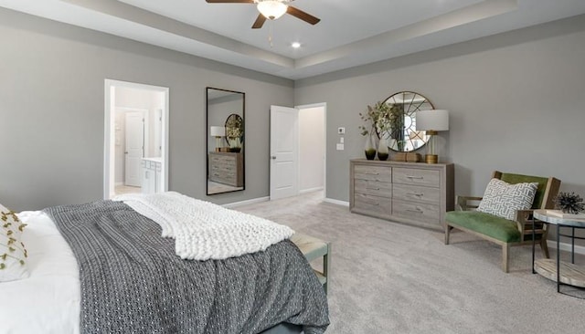 bedroom featuring ceiling fan, light colored carpet, connected bathroom, and a raised ceiling