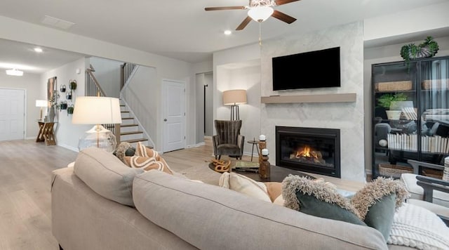 living room featuring ceiling fan, a fireplace, and light hardwood / wood-style flooring