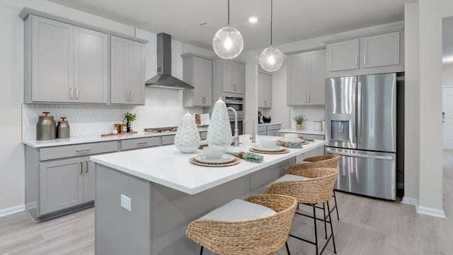 1346 Auburn Glen Rd, Dacula, GA 30019 - kitchen featuring stainless steel appliances, gray cabinetry, wall chimney exhaust hood, a kitchen breakfast bar, and light wood finished floors