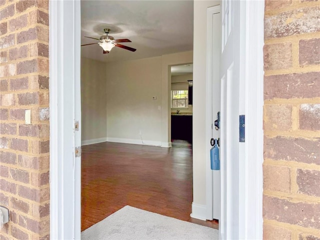 interior space featuring a ceiling fan, wood finished floors, and baseboards