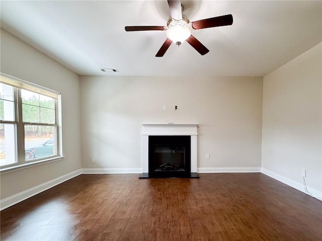 unfurnished living room with visible vents, baseboards, a fireplace with raised hearth, and wood finished floors