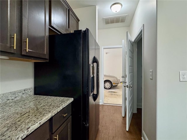 kitchen featuring visible vents, dark wood finished floors, light stone countertops, dark brown cabinets, and black refrigerator with ice dispenser