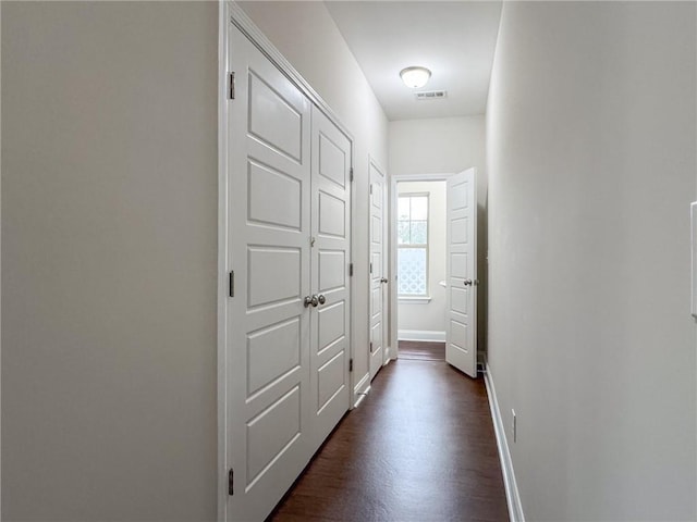 hall with visible vents, dark wood-style flooring, and baseboards