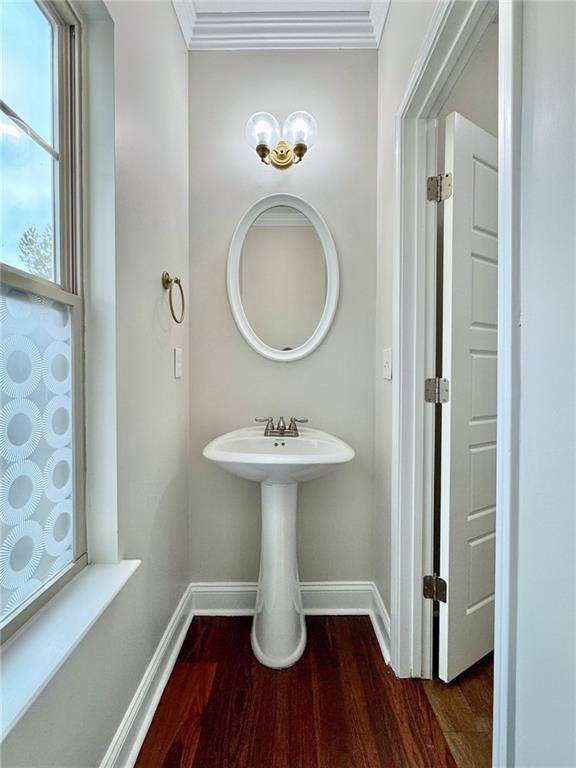 bathroom with baseboards, wood finished floors, and ornamental molding