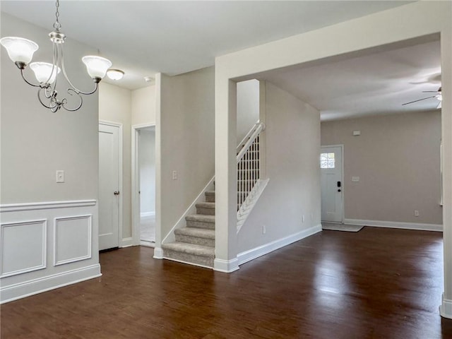 interior space featuring stairs, ceiling fan with notable chandelier, wood finished floors, and baseboards