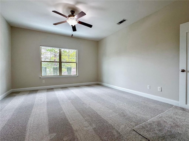 spare room with a ceiling fan, carpet flooring, baseboards, and visible vents