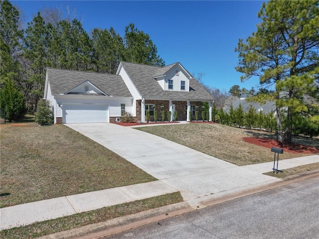 new england style home featuring a front yard, an attached garage, brick siding, and concrete driveway